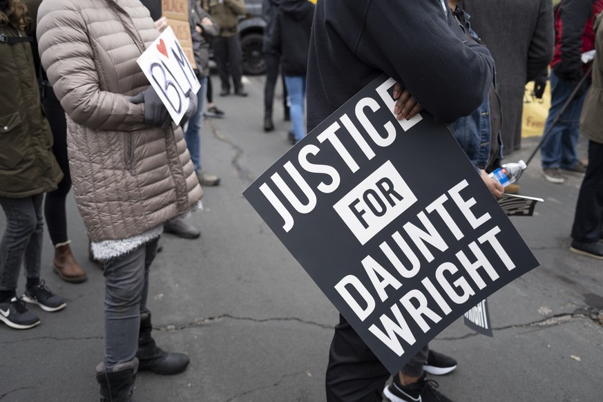 epa09131884 A protester holds a sign reading &#039;Justice for Daunte Wright&#039; outside the Brooklyn Center Police Department after a night of unrest following a fatal officer involved shooting; in ...