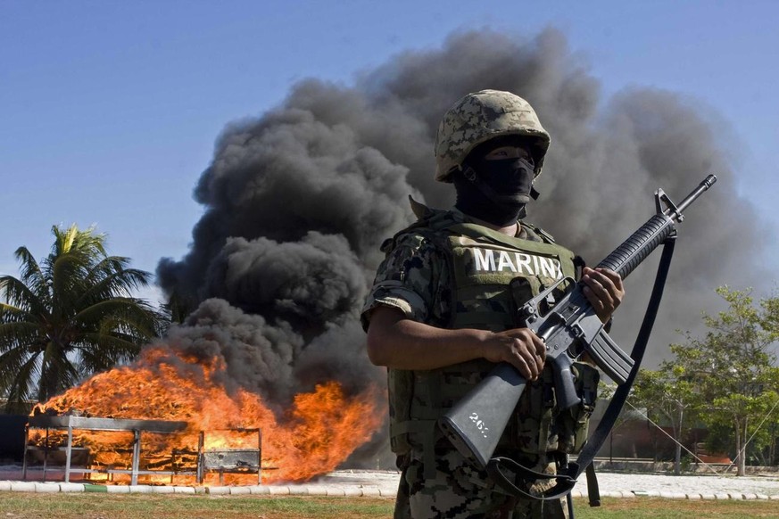 A Mexican Navy sailor stands guard as seized drug is burned in the port town of Progreso, Mexico, Thursday, June 25, 2009. At least a ton of cocaine found inside frozen sharks were incinerated by the  ...