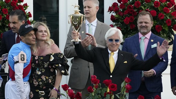 Jockey John Velazquez, left, watches as trainer Bob Baffert holds up the winner&#039;s trophy after they victory with Medina Spirit in the 147th running of the Kentucky Derby at Churchill Downs, Satur ...