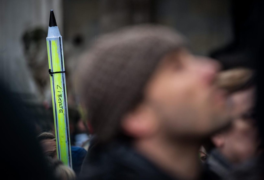 epa04555725 A participant holds a pen with the message &#039;Liberte&#039; (&#039;freedom&#039;) during a solidarity march for victims in Paris, in Munich, Germany, 11 January 2015. According to polic ...