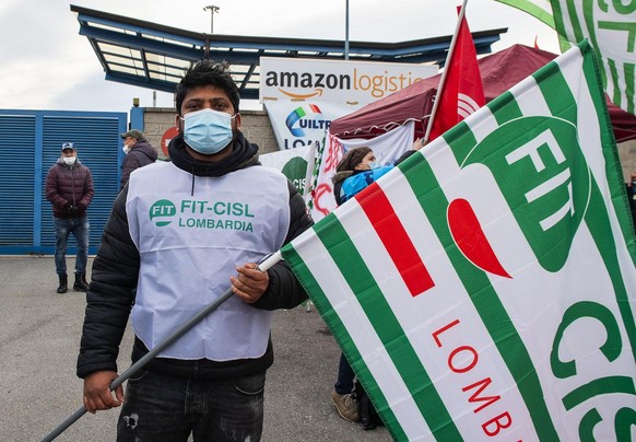 epa09089358 Amazon workers attend a strike as they block deliveries and vehicles in and out of warehouses, in front of the Amazon logistics center HUB at Via Toffetti, in Milan, Italy, 22 March 2021.  ...