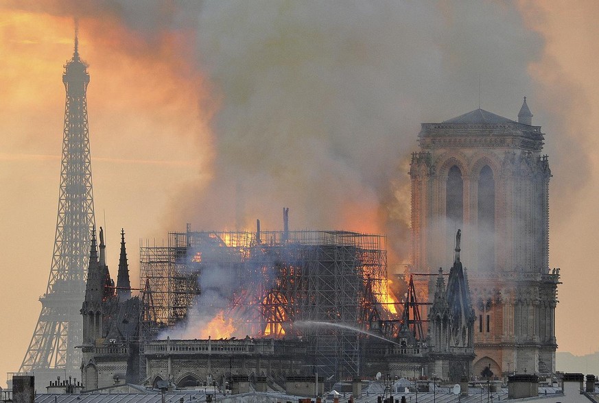 In this image made available on Tuesday April 16, 2019 flames and smoke rise from the blaze after the spire toppled over on Notre Dame cathedral in Paris, Monday, April 15, 2019. An inferno that raged ...