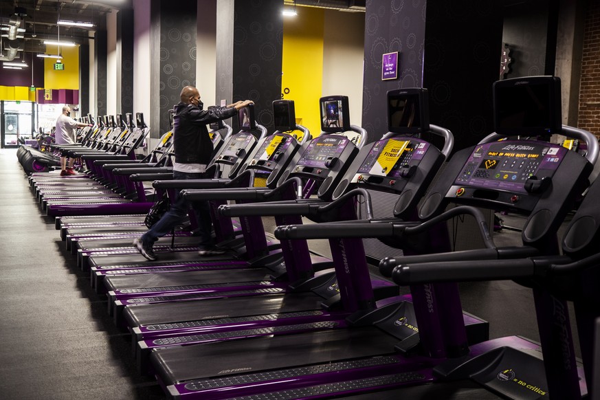 epa09078974 People exercise wearing face masks at Planet Fitness, as the premises reopened amid the coronavirus pandemic in Los Angeles, California, USA, 16 March 2021. Gyms, cinemas, restaurants and  ...
