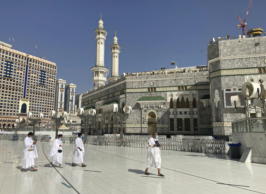 Muslim pilgrims walk outside the Grand Mosque, during the minor pilgrimage, known as Umrah, marking the holy month of Ramadan, in the Muslim holy city of Mecca, Saudi Arabia, Tuesday, April 13, 2021.  ...