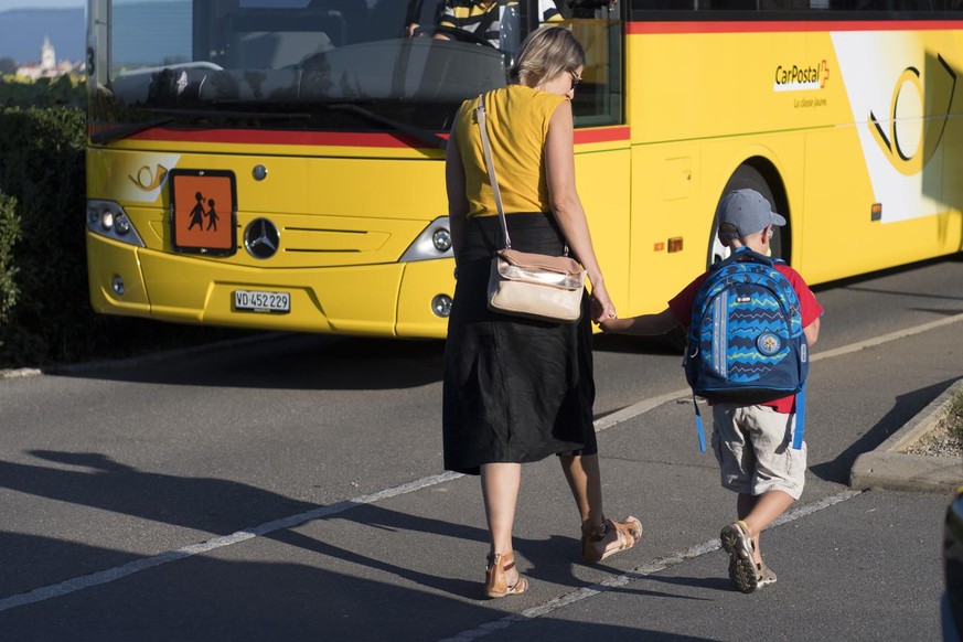 Une maman accompagne son enfant a l?&#039;ecole primaire a cote d?un bus scolaire de Car Postal lors de la rentree scolaire ce lundi 26 aout 2019 a Penthaz. (KEYSTONE/Laurent Gillieron)