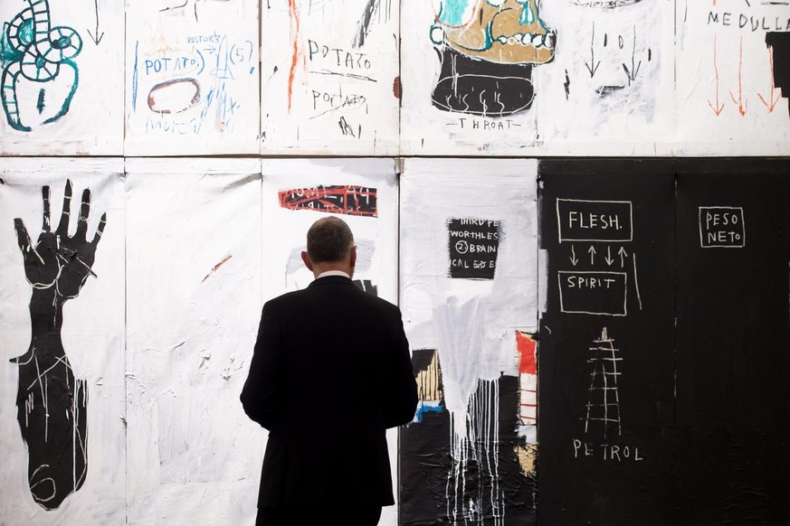 epa06657071 A Sotheby&#039;s employee stands next to &#039;Flesh and Spirit&#039; by American artist Jean-Michel Basquiat (estimated value 30 million US dollars) during a press preview of highlights f ...