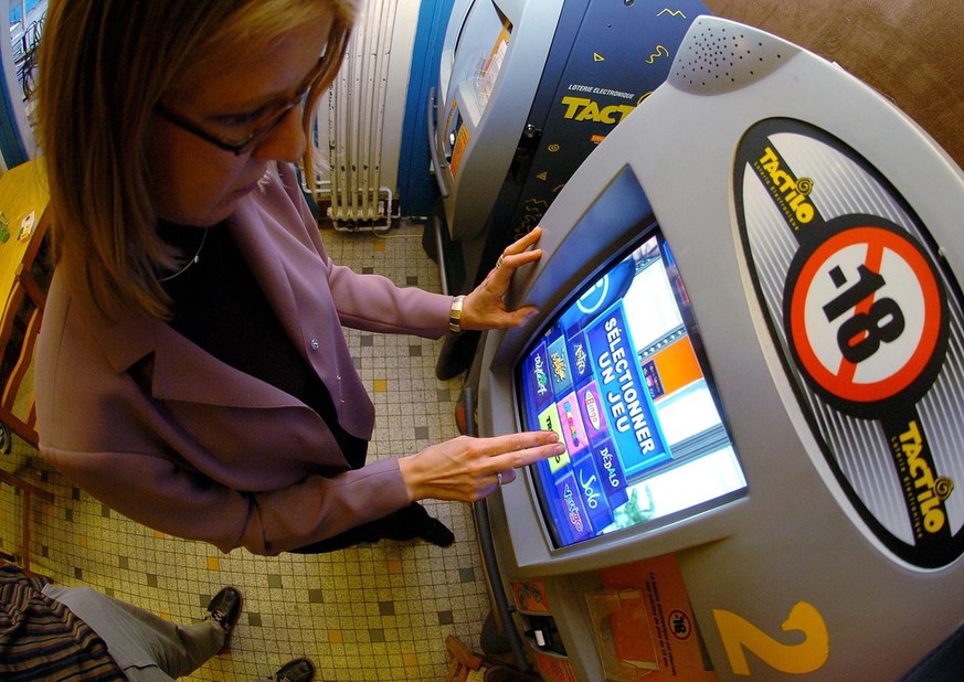 Une charmante jeune fille joue a une machine a sous appeler Tactilo dans restaurant Lausannois, ce samedi 9 octobre 2004. La loterie Tactilo regroupe un ensemble de jeux de loterie auxquels le public  ...
