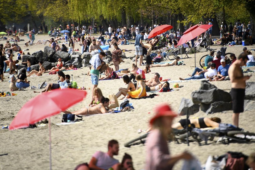 People enjoy the warm spring weather on the shore of the Lake Geneva at the Vidy beach (plage de Vidy) during the coronavirus disease (COVID-19) outbreak, in Lausanne, Switzerland, Sunday, April 25, 2 ...