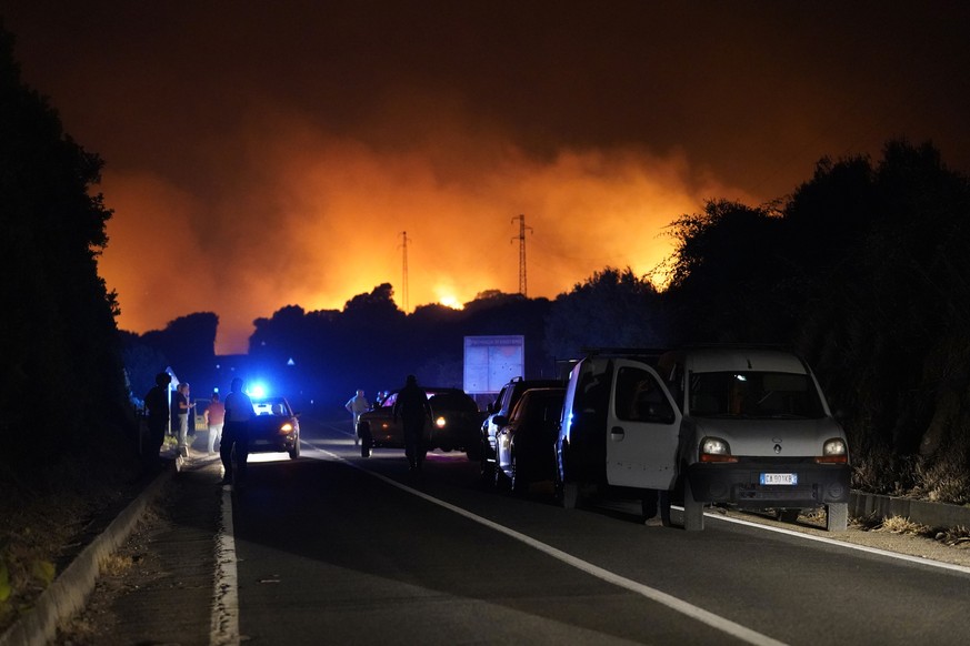 Cars are parked by the road as fires have been raging through the countryside in Cuglieri, near Oristano, Sardinia, Italy, early Sunday, July 25, 2021. Hundreds of people were evacuated from their hom ...