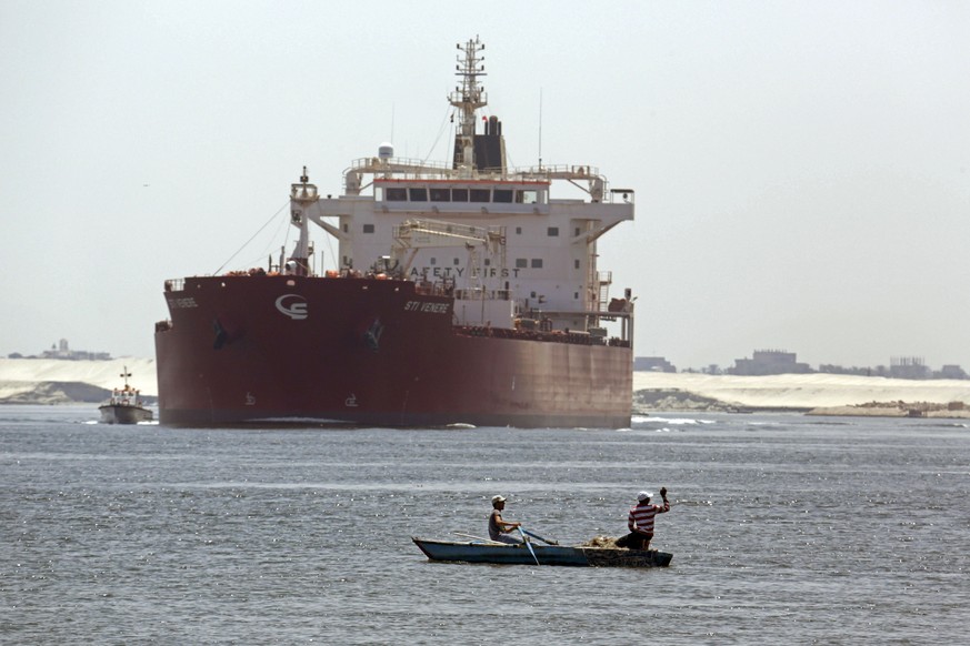 FILE - In this Aug. 12, 2014, file photo, Egyptian fishermen fish in front of a Maltese ship crossing the Suez Canal in Ismailia, Egypt. A massive cargo ship has turned sideways in Egypt&#039;s Suez C ...