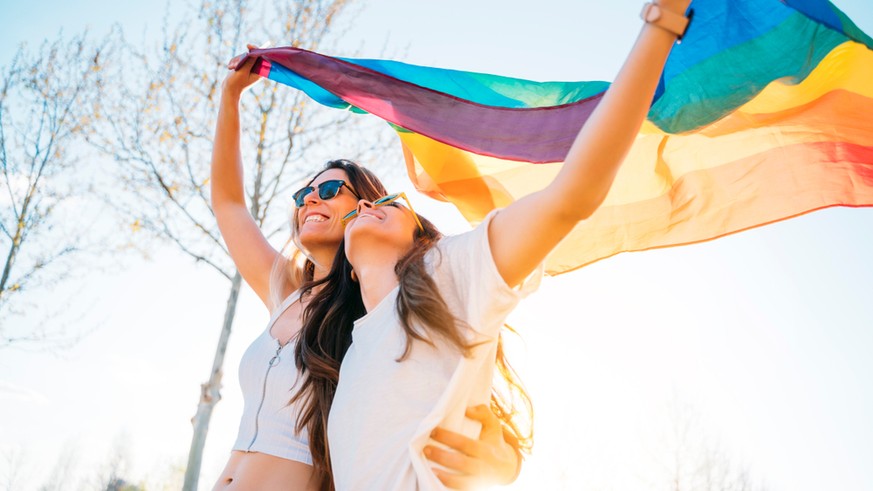 Zwei Frauen mit Regenbogenflagge.