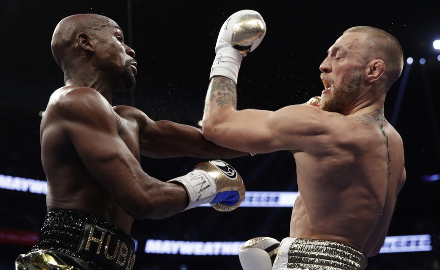 Floyd Mayweather Jr., left, hits Conor McGregor in a super welterweight boxing match Saturday, Aug. 26, 2017, in Las Vegas. (AP Photo/Isaac Brekken)