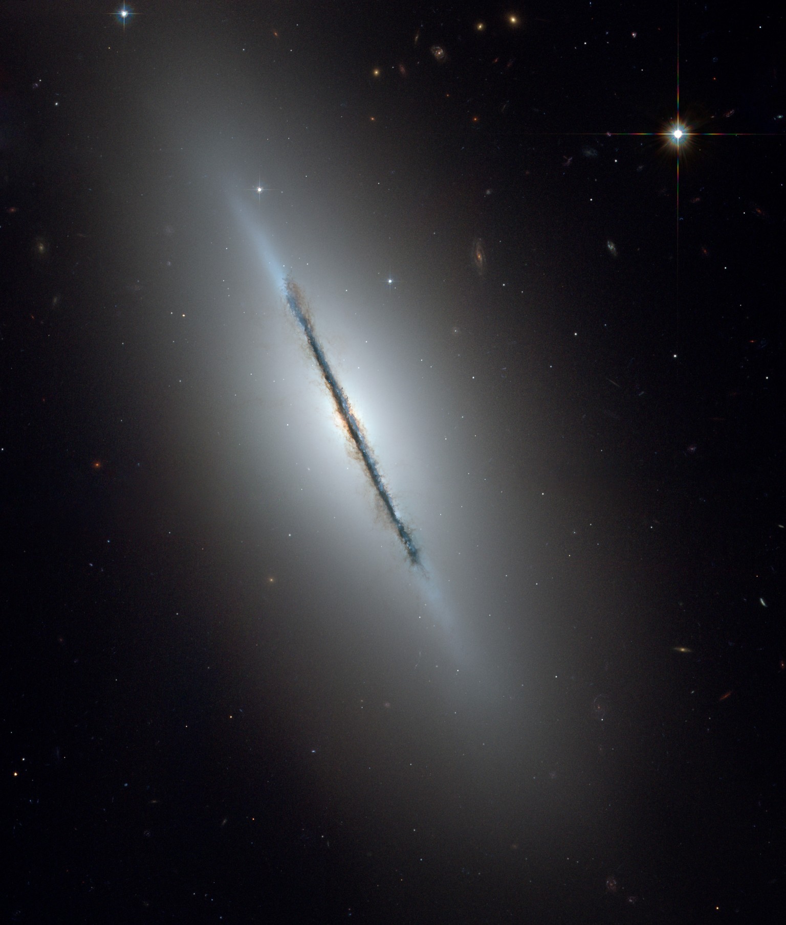 This is a unique NASA/ESA Hubble Space Telescope view of the disk galaxy NGC 5866 tilted nearly edge-on to our line-of-sight. Hubble&#039;s sharp vision reveals a crisp dust lane dividing the galaxy i ...