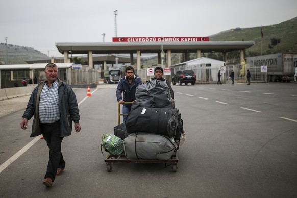 Syrians with their belongings walk into Turkey from Syria at the Cilvegozu border gate with Syria, near the town of Hatay, southeastern Turkey, Friday, Feb. 28, 2020. NATO envoys were holding emergenc ...