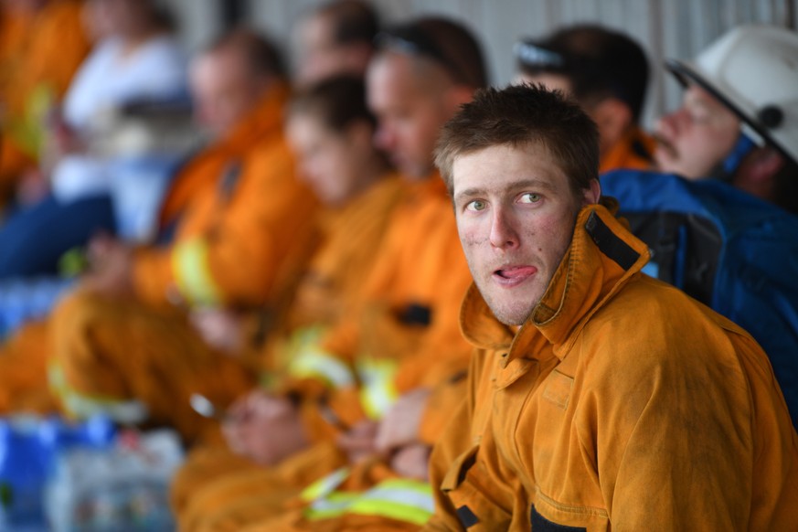 epa08115465 Firefighters rest at Kingscote oval after fighting fires through the night, on Kangaroo Island, southwest of Adelaide, Australia, 10 January 2020. Country Fire Service volunteers along wit ...