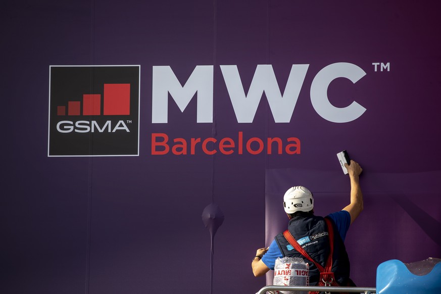 A worker fixes a poster announcing the Mobile World Congress 2020 in a conference venue in Barcelona, Spain, Tuesday, Feb. 11, 2020. Intel Mobile is the latest company announcing that is pulling out o ...