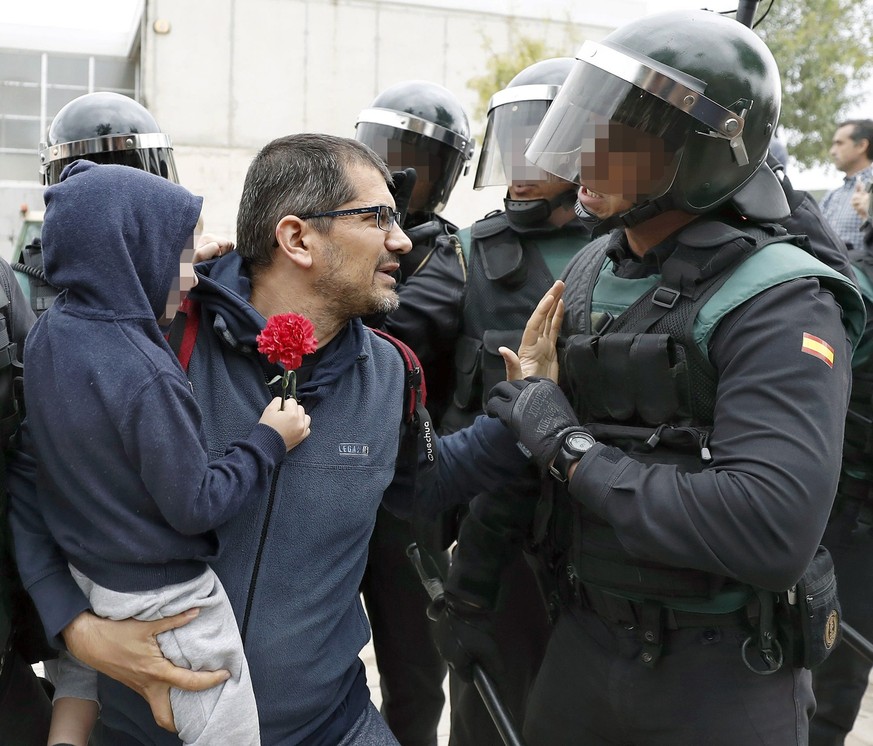 epa06237481 A Catalan man with his child in his arms argues with a Spanish National riot policemen during clashes outside the Ramon Llull school during the &#039;1-O Referendum&#039; in Barcelona, Cat ...