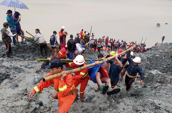 epaselect epa08522221 A handout photo made available by the Myanmar Fire Services Department shows rescue workers carrying the body of a victim after a landslide accident at a jade mining site in Hpak ...