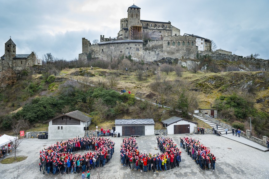 People form the word &quot;Oui&quot; yes in French after making a human chain during a major event in support of the bid for the 2026 Sion Olympic Games between the castle of Tourbillon and the Basili ...