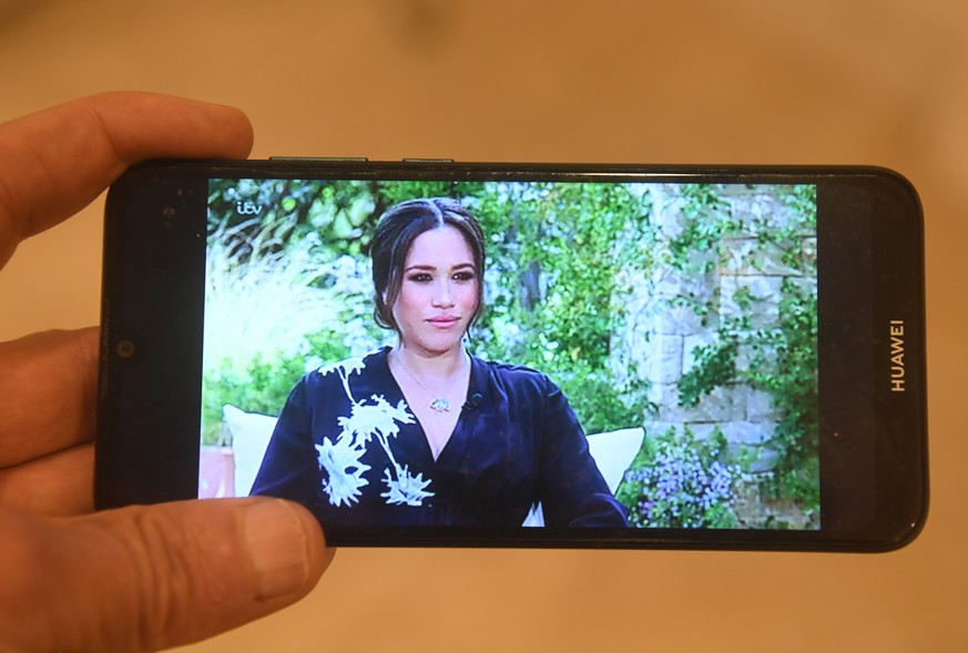 epa09062891 A person watches on a mobile phone the ITV broadcast in the UK of the interview by US talk show host Oprah Winfrey with Britain&#039;s Prince Harry and Meghan Markle, the Duke and Duchess  ...