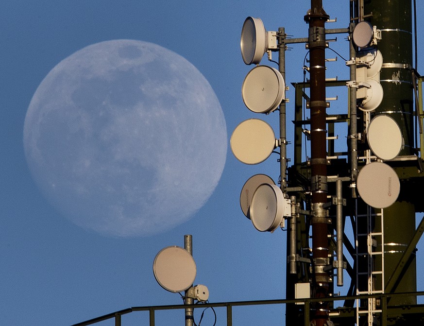 The moon rises behind a mobile radio mast in Wachenbuchen near Frankfurt, Germany, Tuesday, March 19, 2019. Germany began auctioning frequencies for the future super-fast 5G network on Tuesday, amid f ...