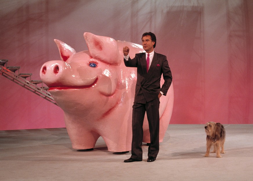 Der Schweizer Fernseh-Moderator Kurt Felix und sein Hund Sheriff vor einem riesigen Sparschwein waehrend einer Probe fuer die TV-Sendung &quot;Supertreffer&quot;, aufgenommen 1987 in Flims, Graubuende ...