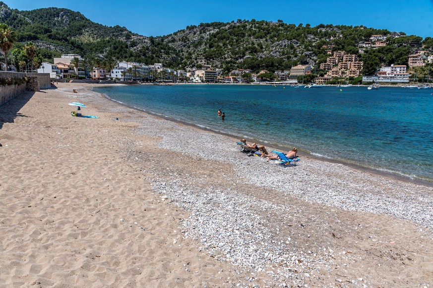epa08508789 Sunbathers enjoy the weather at Soller beach in Palma de Mallorca, Balearic Islands, Spain, 25 June 2020. The absence of tourists has left unusual images of Bealearic beaches almost empty  ...