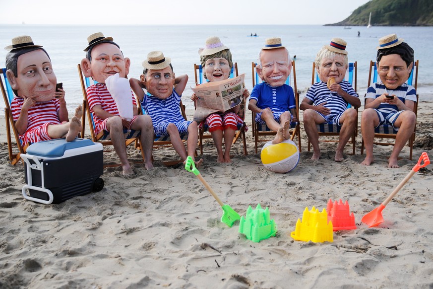 epa09263908 Oxfam activists wearing papier-mache heads depicting G7 leaders perform during a protest at Swanpool Beach near Falmouth, during the G7 summit, in Cornwall, Britain, 12 June 2021. EPA/PHIL ...
