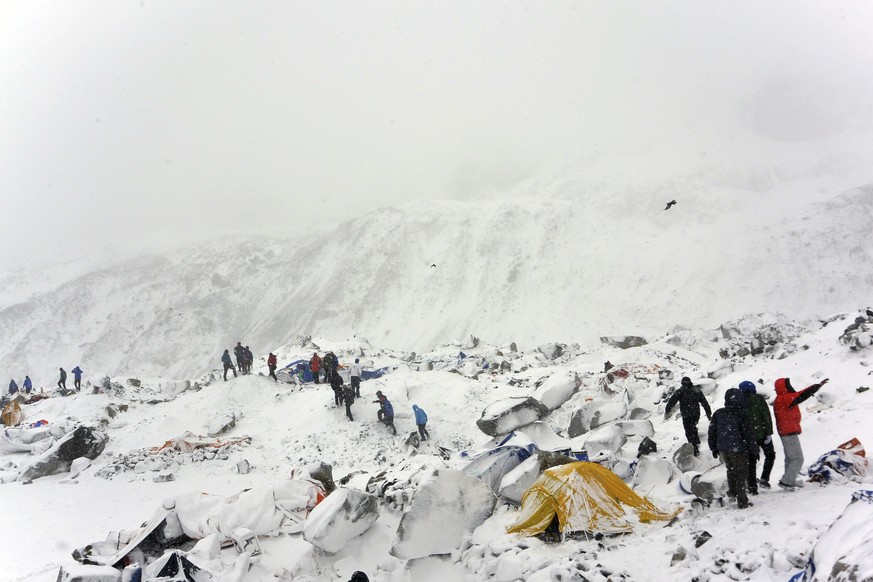 In this Saturday, April 25, 2015 photo, climbers search through crushed tents for fellow climbers caught in an avalanche at a base camp on the Nepal side of Mount Everest. Set off by a magnitude 7.8 e ...