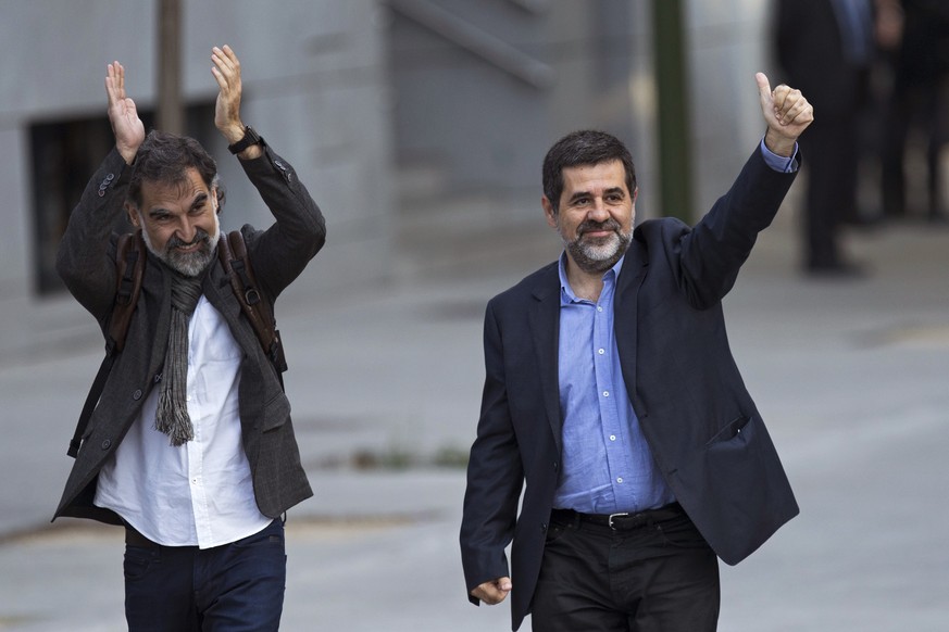 Jordi Cuixart, president of the Catalan Omnium Cultural organization, left, and Jordi Sanchez, president of the Catalan National Assembly wave to supporters on arrival at the national court in Madrid, ...