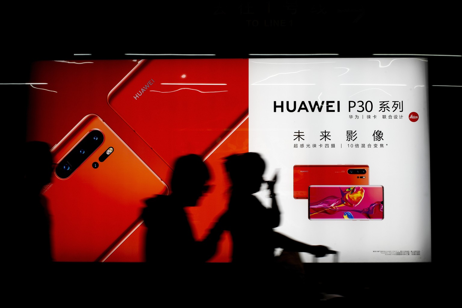 Commuters walk by the new Huawei P30 smartphone advertisement on display inside a subway station in Beijing Monday, May 13, 2019. China&#039;s intensified tariff war with the Trump administration is t ...
