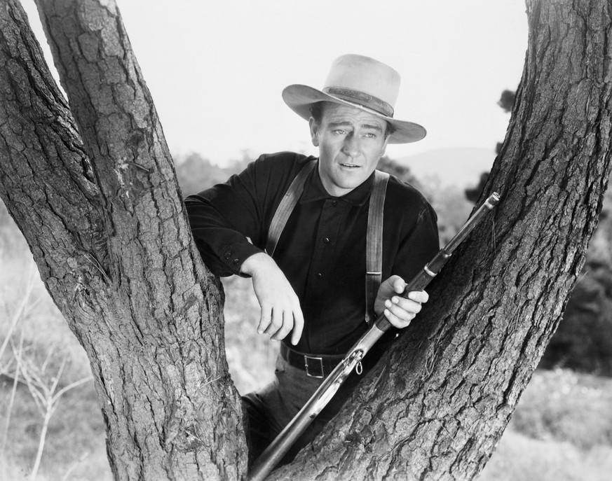 (Original Caption) 1940-John Wayne as he appeared in the film &quot;Shepherd of the Hills: resting his rifle in the fork of a tree. Photograph, 1940. Movie Still. Movie released in 1941. (Photo by AS4 ...