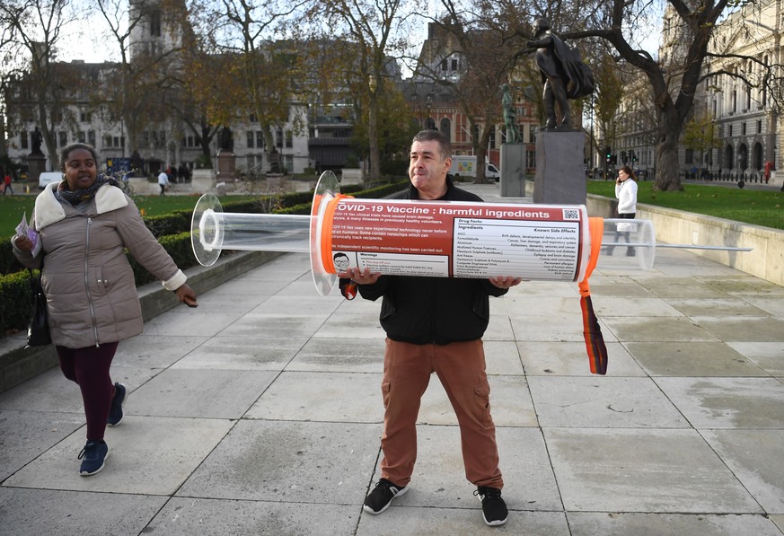 epa08839320 A man holds an oversized syringe after protesting against Covid-19 vaccination, outside the headquarters of the Bill and Melinda Gates Foundation in London, Britain, 24 November 2020. Vacc ...