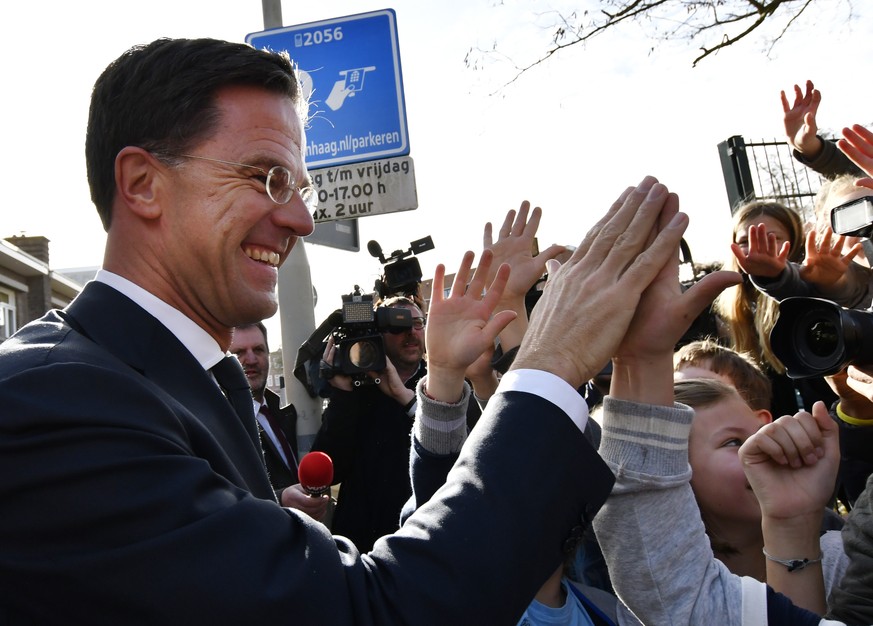 Dutch Prime Minister Mark Rutte gives &#039;high five&#039; to children after casting his vote for the Dutch general election in The Hague, Netherlands, Wednesday, March 15, 2017. (AP Photo/Patrick Po ...