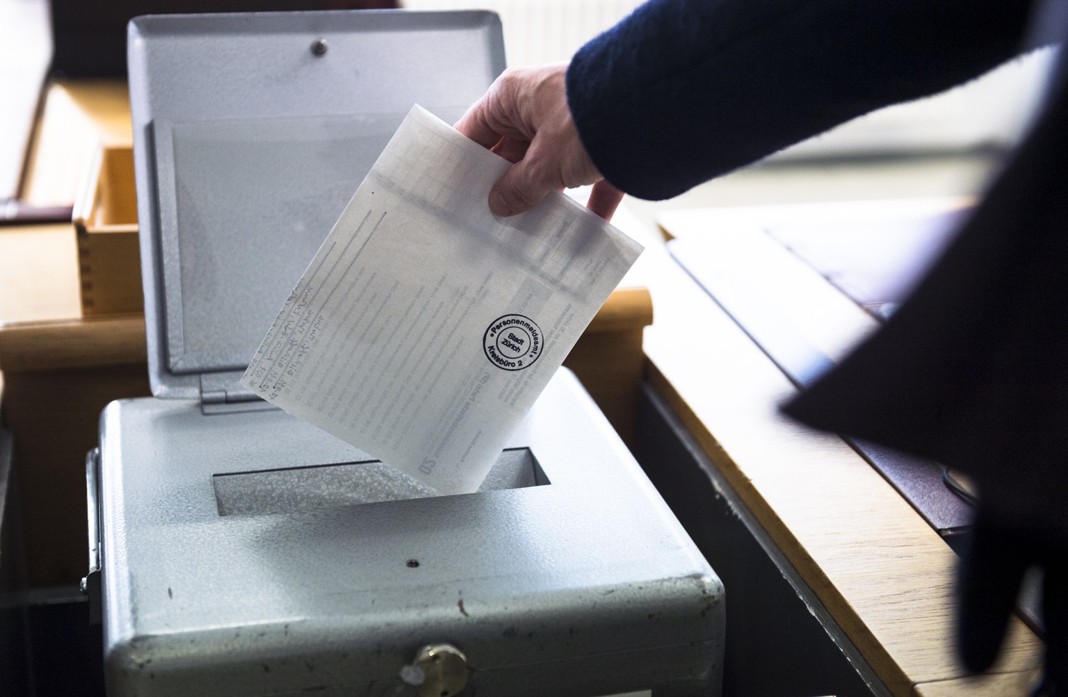 Eine Waehlerin wirft ihren Wahlzettel fuer die Erneuerungswahl der 35 zuercherischen Mitglieder des schweizerischen Nationalrates, Wahl vom 18. Oktober 2015, in die Wahlurne auf einem Kreisbuero der S ...