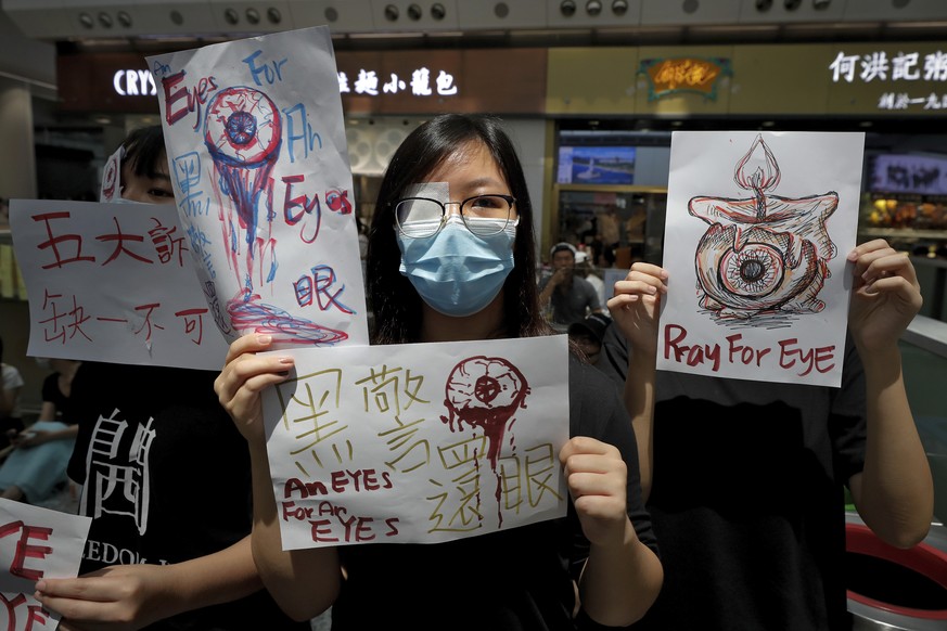 People hold signs which read &quot; Black Police, Return eye,&quot; bottom center, during a protest at the arrival hall of the Hong Kong International airport in Hong Kong, Monday, Aug. 12, 2019. It i ...