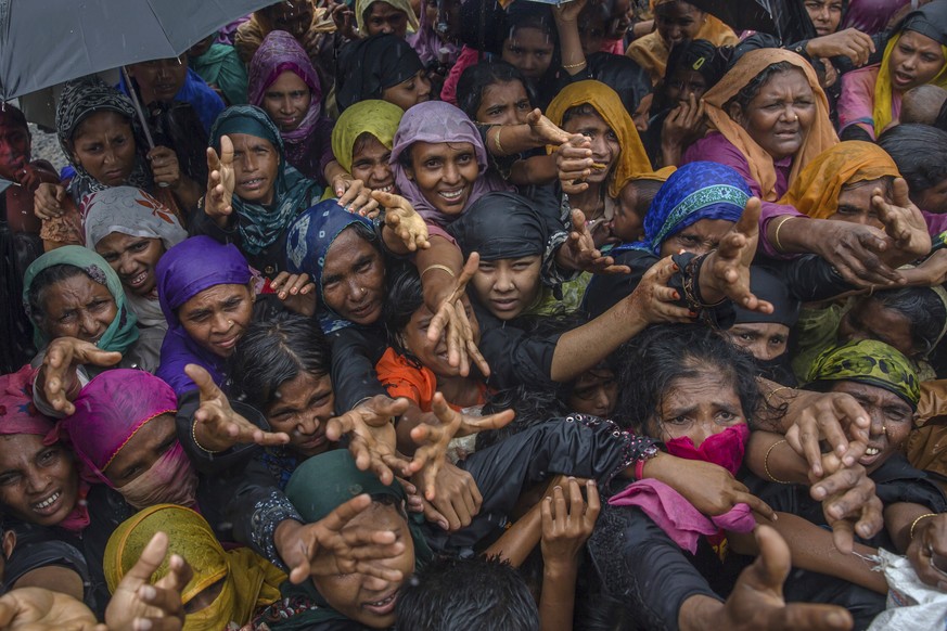 FILE - In this file photo dated Sunday, Sept. 17, 2017, Rohingya Muslim women, who crossed over from Myanmar into Bangladesh, stretch their arms out to collect sanitary products distributed by aid age ...