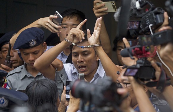 Reuters journalist Kyaw Soe Oo, center, talks to journalists during he is escorted by polices as they leave the court Monday, Sept. 3, 2018, in Yangon, Myanmar. A Myanmar court sentenced two Reuters j ...