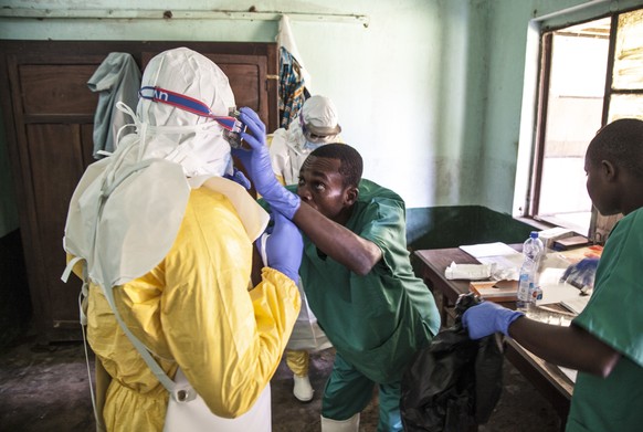 In this photo taken Saturday, May 12, 2018, health workers don protective clothing as they prepare to attend to patients in the isolation ward to diagnose and treat suspected Ebola patients, at Bikoro ...