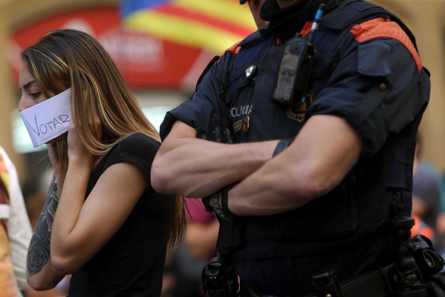 epa06215993 A woman protest next to a Catalan Police officer at the Catalan Foreign ministry regional seat in Barcelona, Catalonia, northeastern Spain, 20 September 2017. Spanish Civil Guard carried o ...