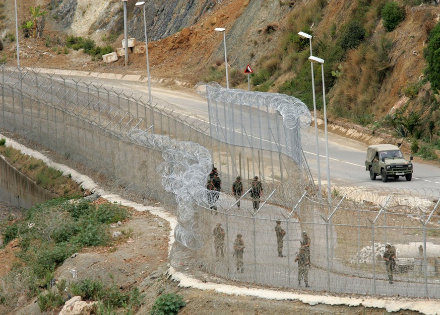 Soldiers patrol the razor wired fences seperating Morocco and Spain&#039;s North African enclave of Ceuta on the Moroccan border, Monday, Oct. 3, 2005. Soldiers with automatic weapons and police with  ...