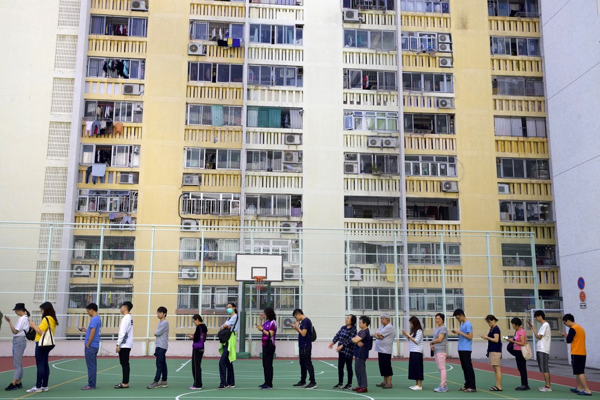 People line up to vote outside of a polling place at a housing estate in Hong Kong, Sunday, Nov. 24, 2019. Long lines formed outside Hong Kong polling stations Sunday in elections that have become a b ...