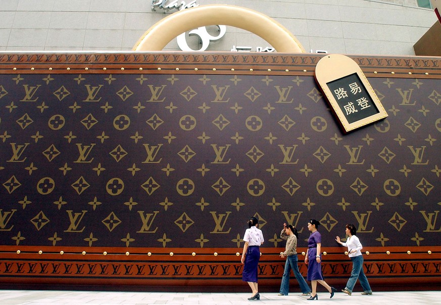 People walk past a big lagguage-like advertisement of Louis Vuitton Friday June 4, 2004 in Shanghai, China. Shanghai became home to an army of foreign designer boutiques targeting the new rich of Chin ...
