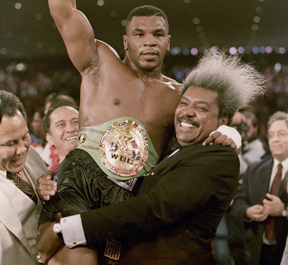 FILE - In this Nov. 22, 1986, file photo, boxing promoter Don King lifts new heavyweight champion Mike Tyson after Tyson defeated Trevor Berbick in Las Vegas. At one time he was the baddest man on the ...