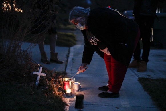 A neighbor lights a candle at a small memorial near the site of the fatal police shooting of Andre Hill on Wednesday, Dec. 23, 2020 on Oberlin Drive in Columbus, Ohio. Hill, 47, was shot and killed by ...