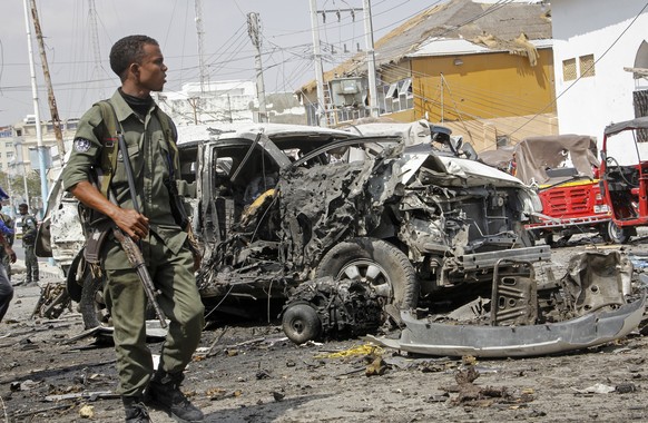A member of the security forces walks past wreckage at the scene of a bombing in Mogadishu, Somalia Saturday, Feb. 13, 2021. Police say a suicide bomber died and a number of civilians were wounded whe ...