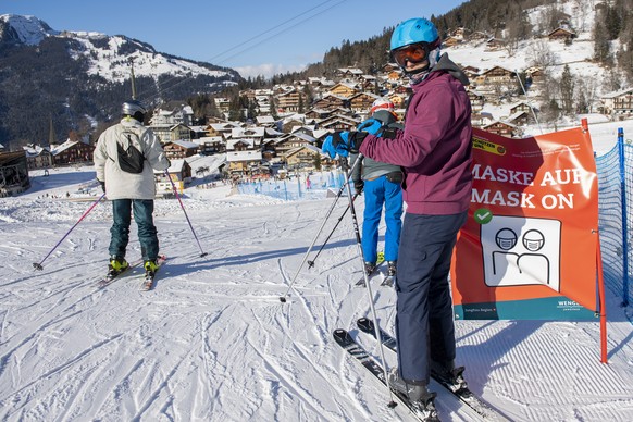 Skifahrer mit Schutzmaske im Dorf Wengen, aufgenommen am Freitag, 8. Januar 2021, im Skigebiet Grindelwald - Wengen. Die Berner Skigebiete bleiben trotz Coronavirus geoeffnet, mit reduzierter Transpor ...