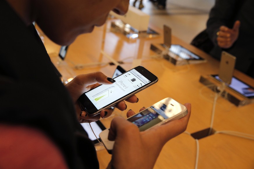 FILE - In this Sept. 19, 2014 file photo, a customer checks out the new iPhone 6 at an Apple store in Paris. Apple&#039;s iPhones and iPads are getting free software updates Wednesday, Sept. 16, 2015, ...