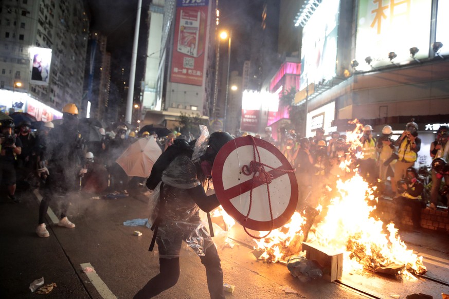 A protestor uses a shield to cover himself as he faces policemen in Hong Kong, Saturday, Aug. 31, 2019. Protesters and police are standing off in Hong Kong on a street that runs through the bustling C ...