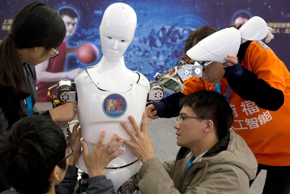 FILE - In this Oct. 21, 2016, file photo, Chinese students work on the Ares, a humanoid bipedal robot designed by them with fundings from a Shanghai investment company, displayed during the World Robo ...